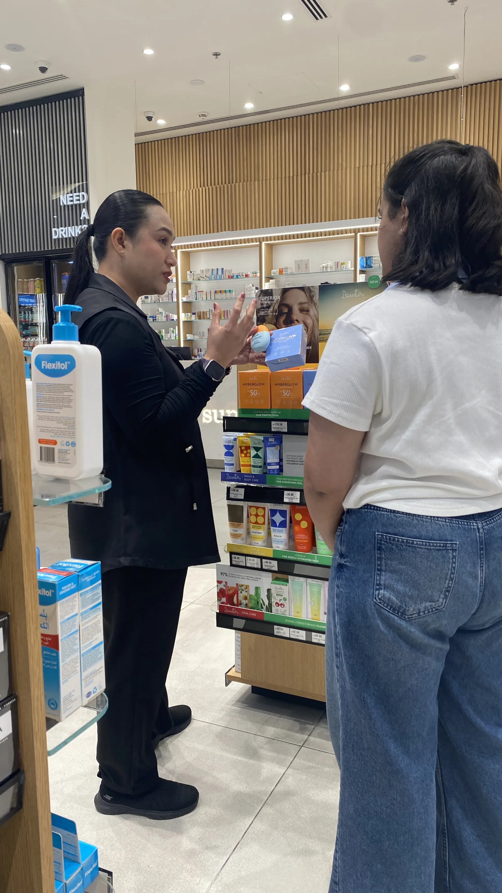 A brand ambassador talking a customer through a skincare product in a pharmacy aisle.