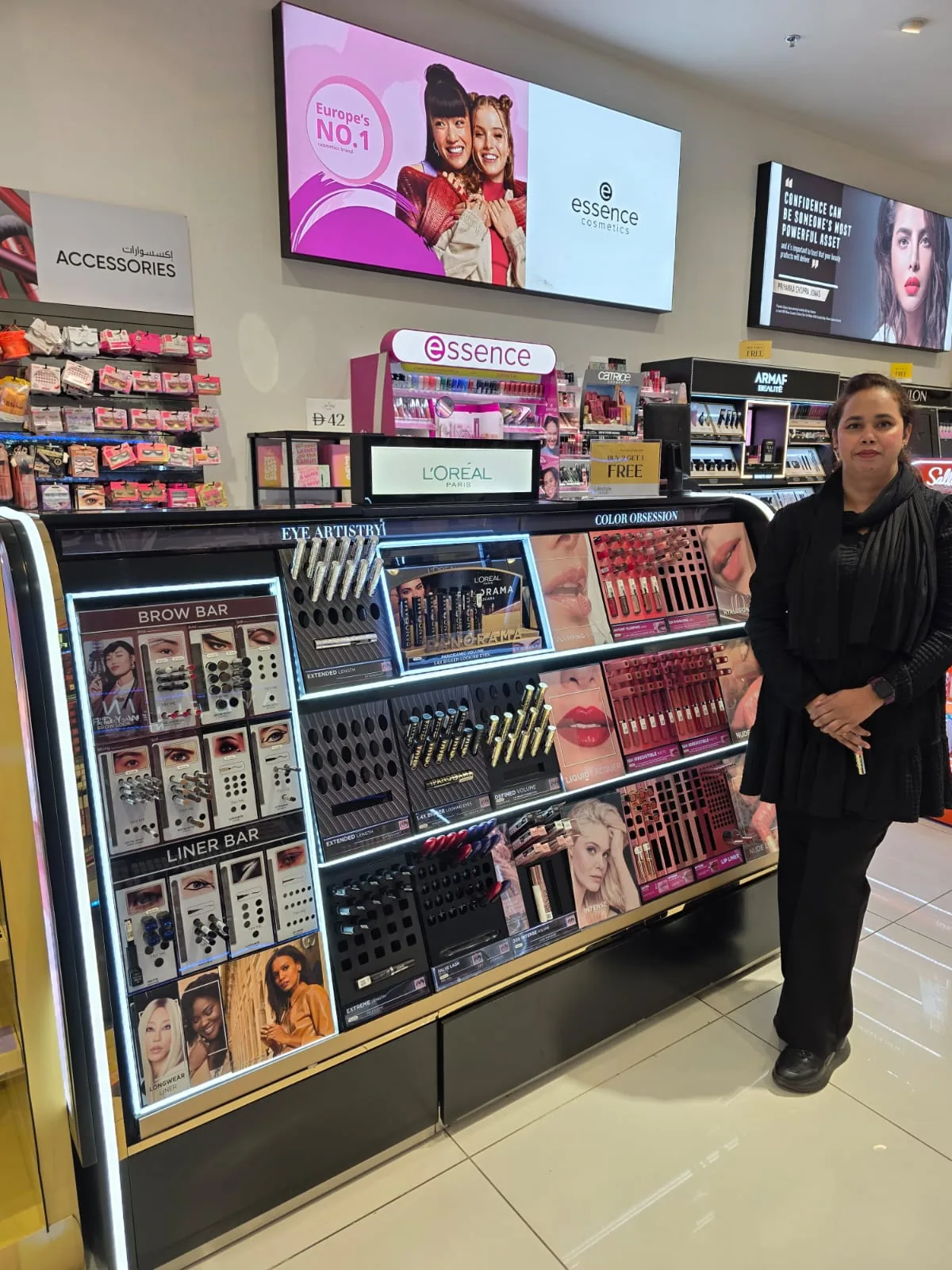 A beauty advisor beside the L'Oréal cosmetics display at the beauty hall.