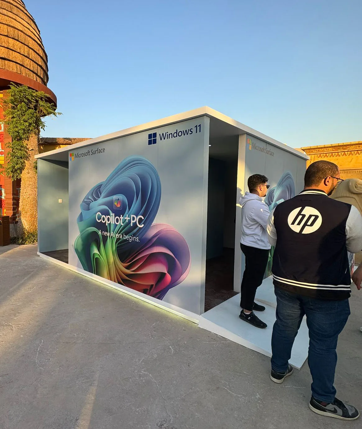 Visitors at the entrance of the Copilot+ PC pop-up, its exterior wrapped in Microsoft Surface, Windows 11 and Copilot+ PC branding.