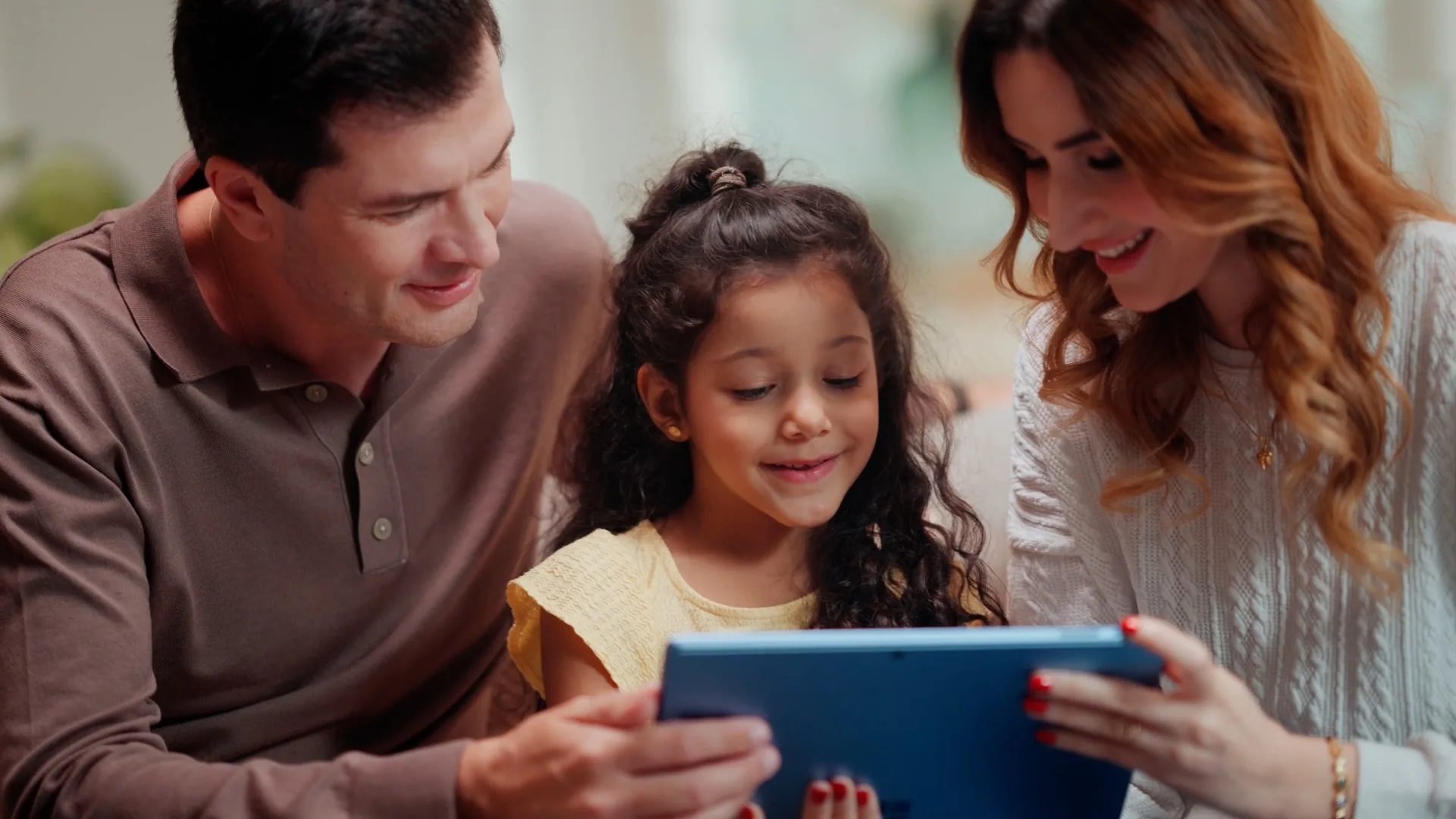 A family gathered around a blue Surface, a child smiling at the screen