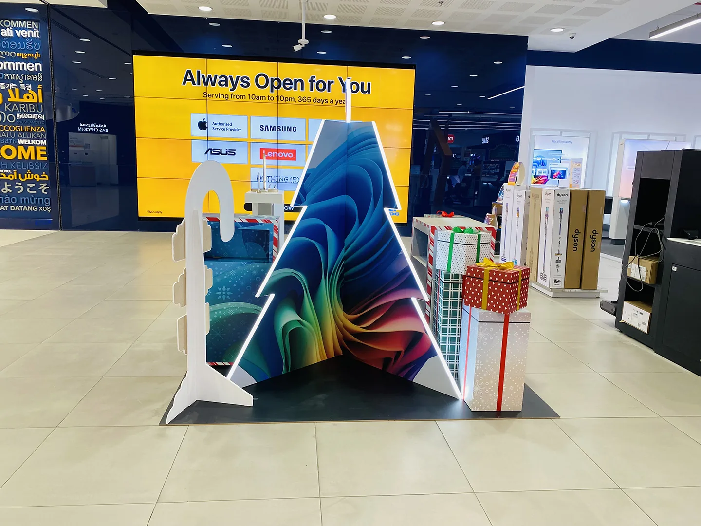 A Copilot+PC festive tree installation with a Windows 11 bloom graphic on a mall concourse