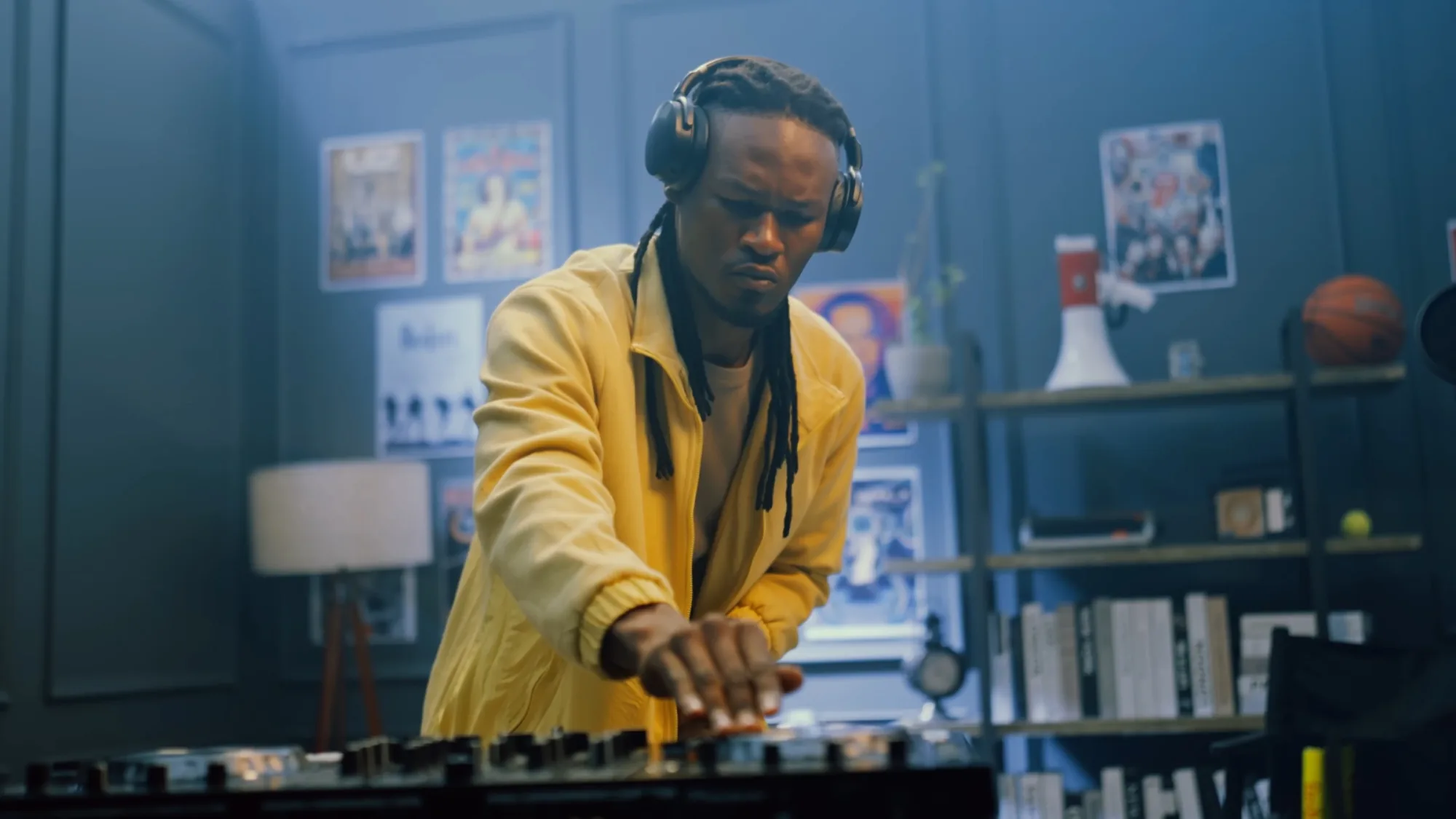 A young musician in a yellow jacket mixing tracks, headphones on