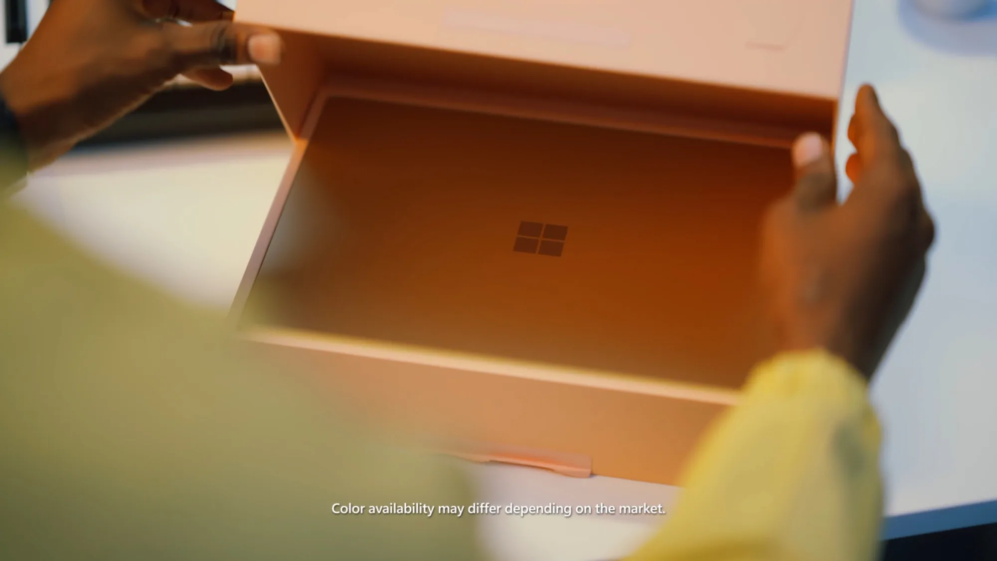 Hands unboxing a copper-toned Surface Copilot+PC