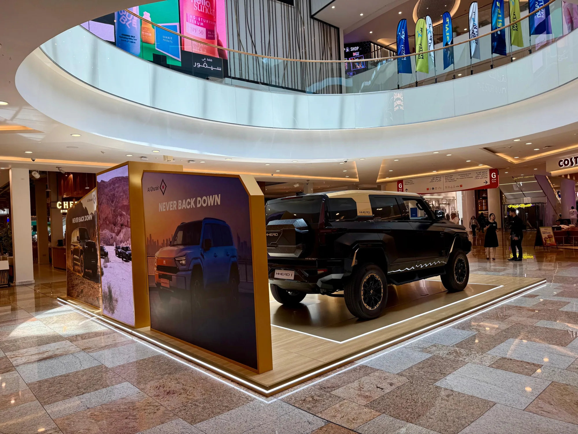 Wide view of the indoor MHERO stand with the 'Never Back Down' campaign backdrop.