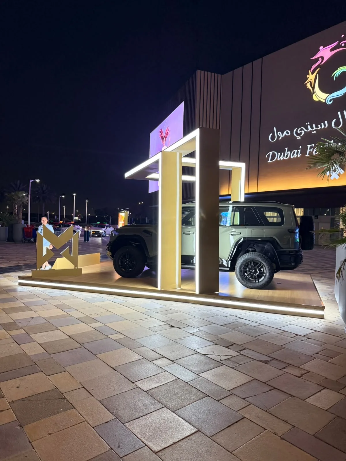The MHERO II under the illuminated gold frame of the outdoor stand at night.