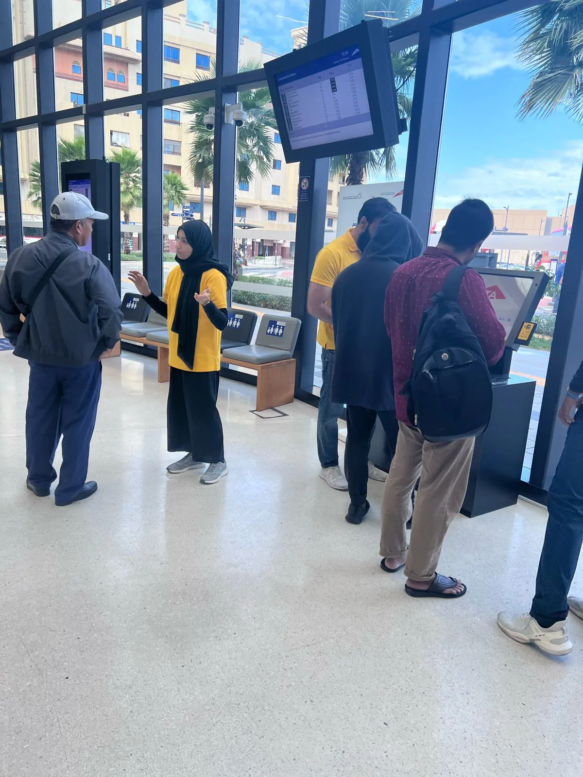 An UmbraCity brand ambassador explaining the umbrella-sharing service to commuters at a Dubai station.