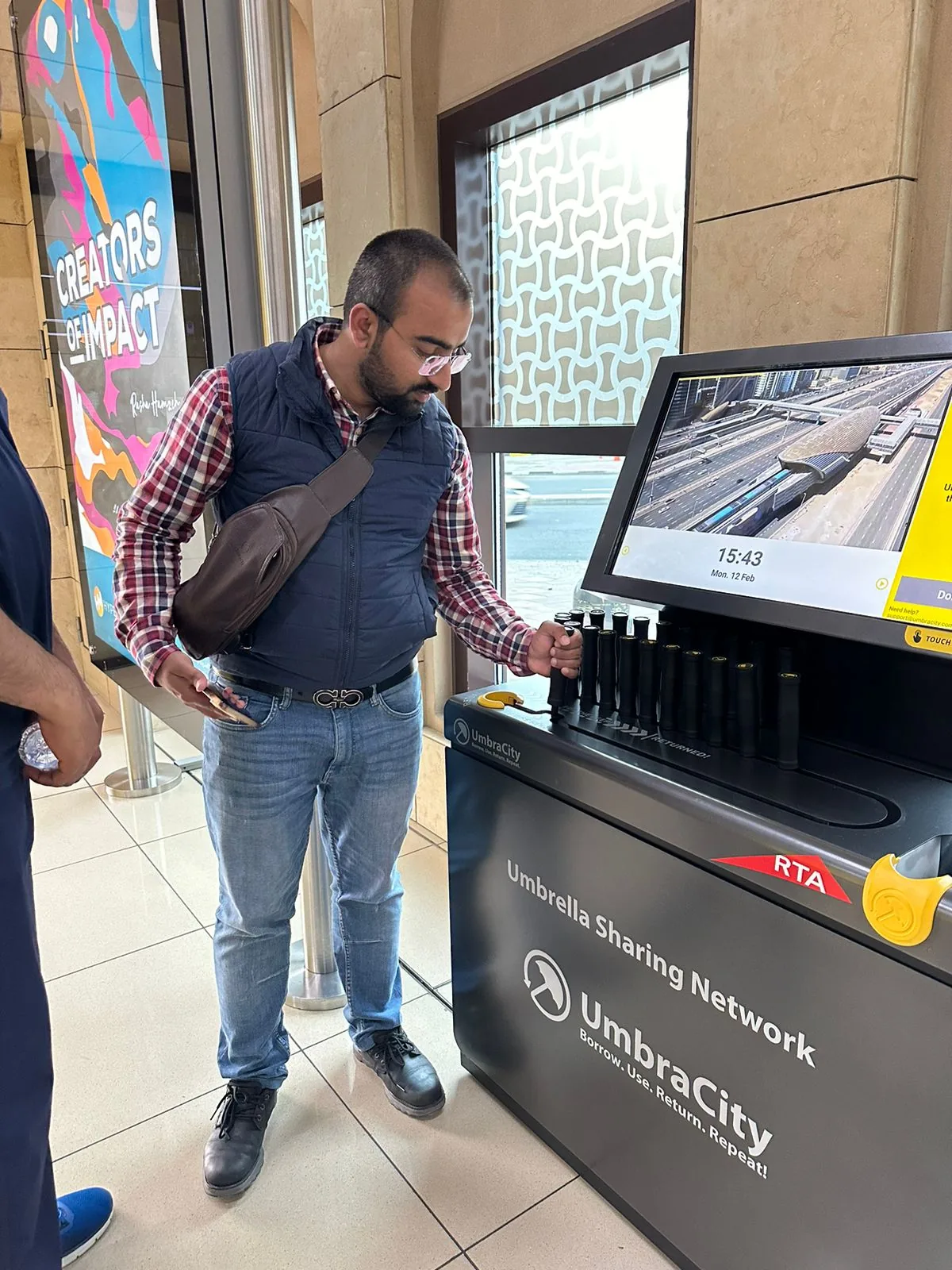 A commuter using the UmbraCity “Borrow. Use. Return. Repeat” kiosk at a Dubai station.