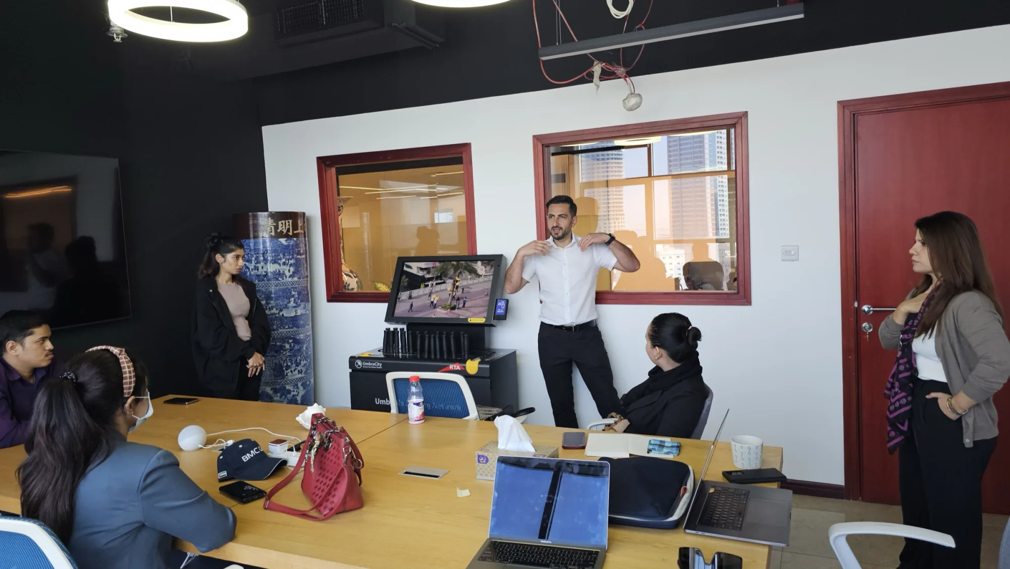 Promocell leading an UmbraCity staff-training session in a Dubai office, the umbrella-sharing kiosk set up in the room.